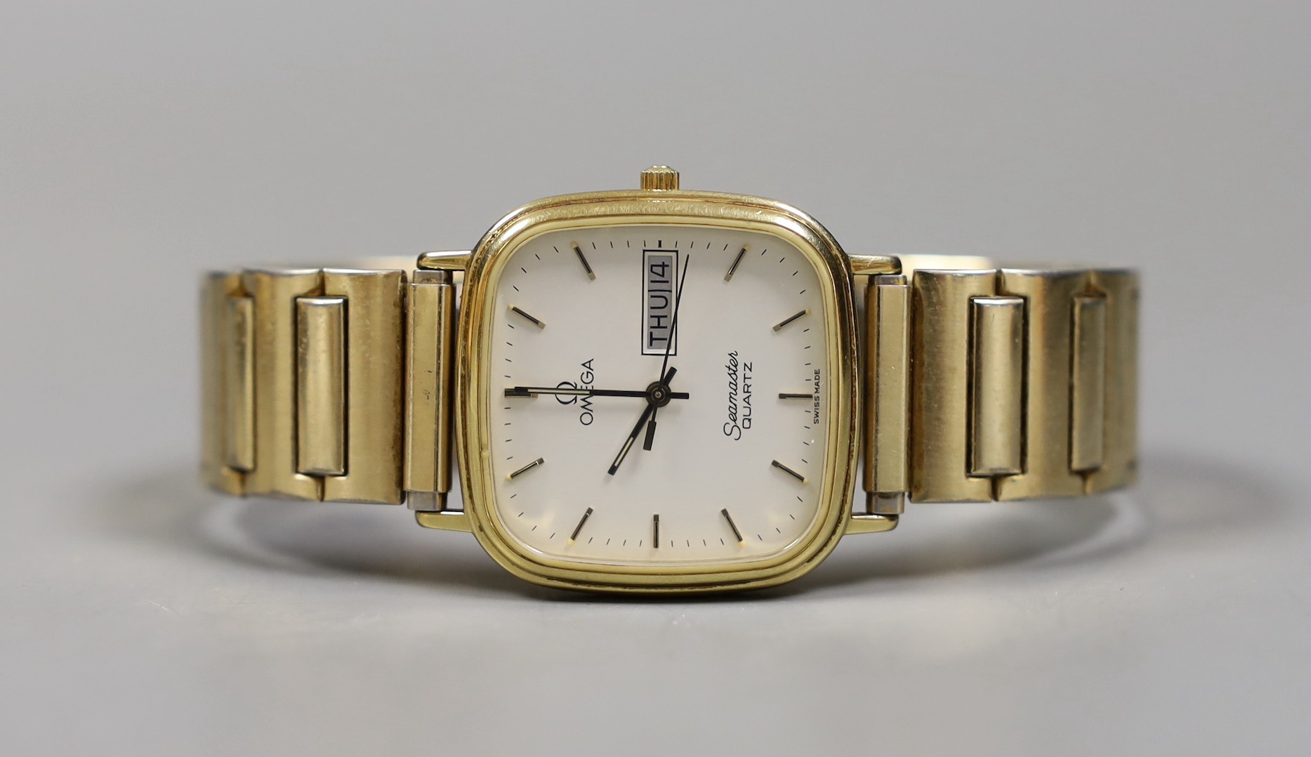 A gentleman's gold plated Omega Seamaster day/date quartz wrist watch, on associated flexible bracelet.